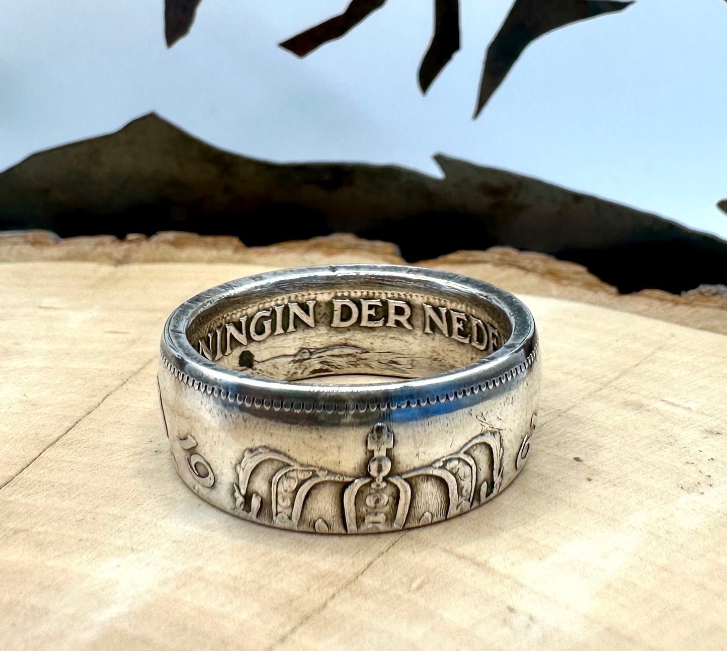 Netherlands 2.5 Gulden Silver Coin Ring on a light wood round with a metal mountain background. - Mountainstruck Coin Jewelry