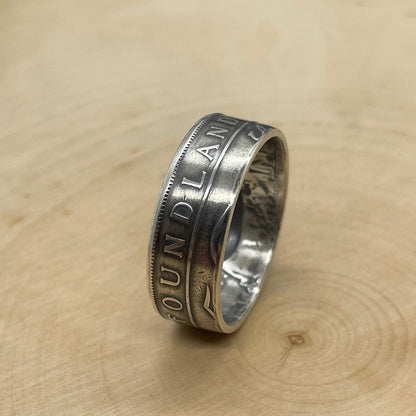 Newfoundland 50 Cents Silver Coin Ring on its edge on a light wood round. - Mountainstruck Coin Jewelry