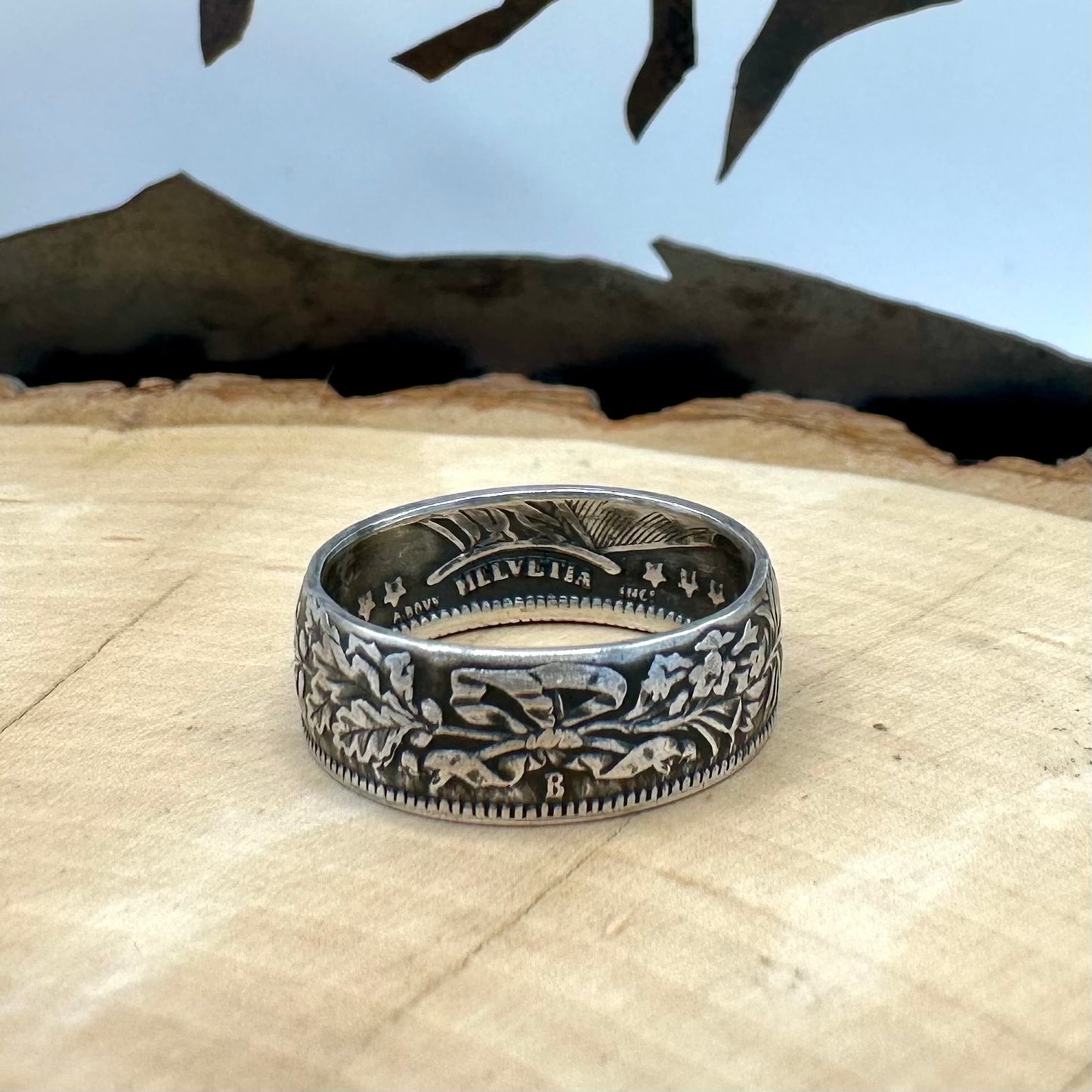 Swiss 1 Franc Silver Coin Ring patina on a light wood round. - Mountainstruck Coin Jewelry