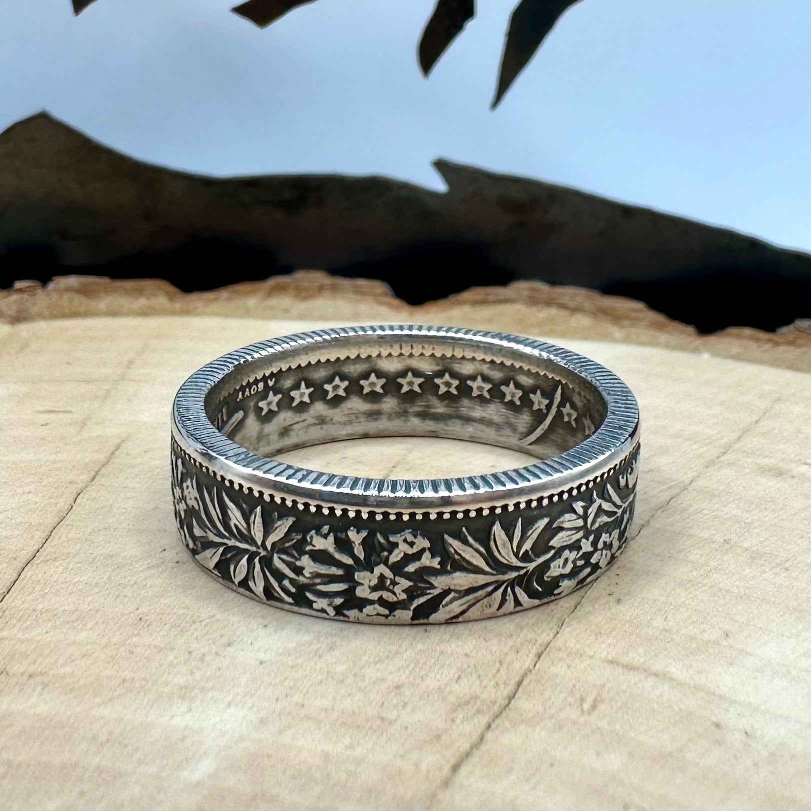 Swiss 2 Franc Silver Coin Ring (patina) on a light wood round with mountain outline in the background. - Mountainstruck Coin Jewelry