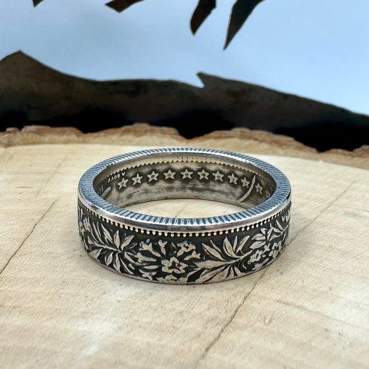 Swiss 2 Franc Silver Coin Ring (patina) on a light wood round with mountain outline in the background. - Mountainstruck Coin Jewelry