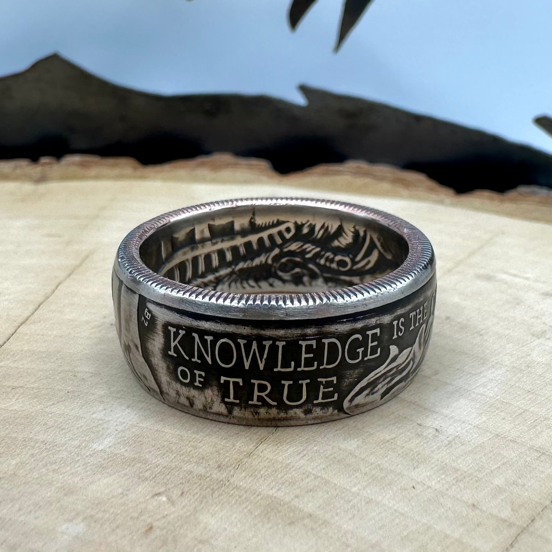 U.S. 2026 Half Dollar Coin Ring on a light wood round with a metal mountain background. - Mountainstruck Coin Jewelry
