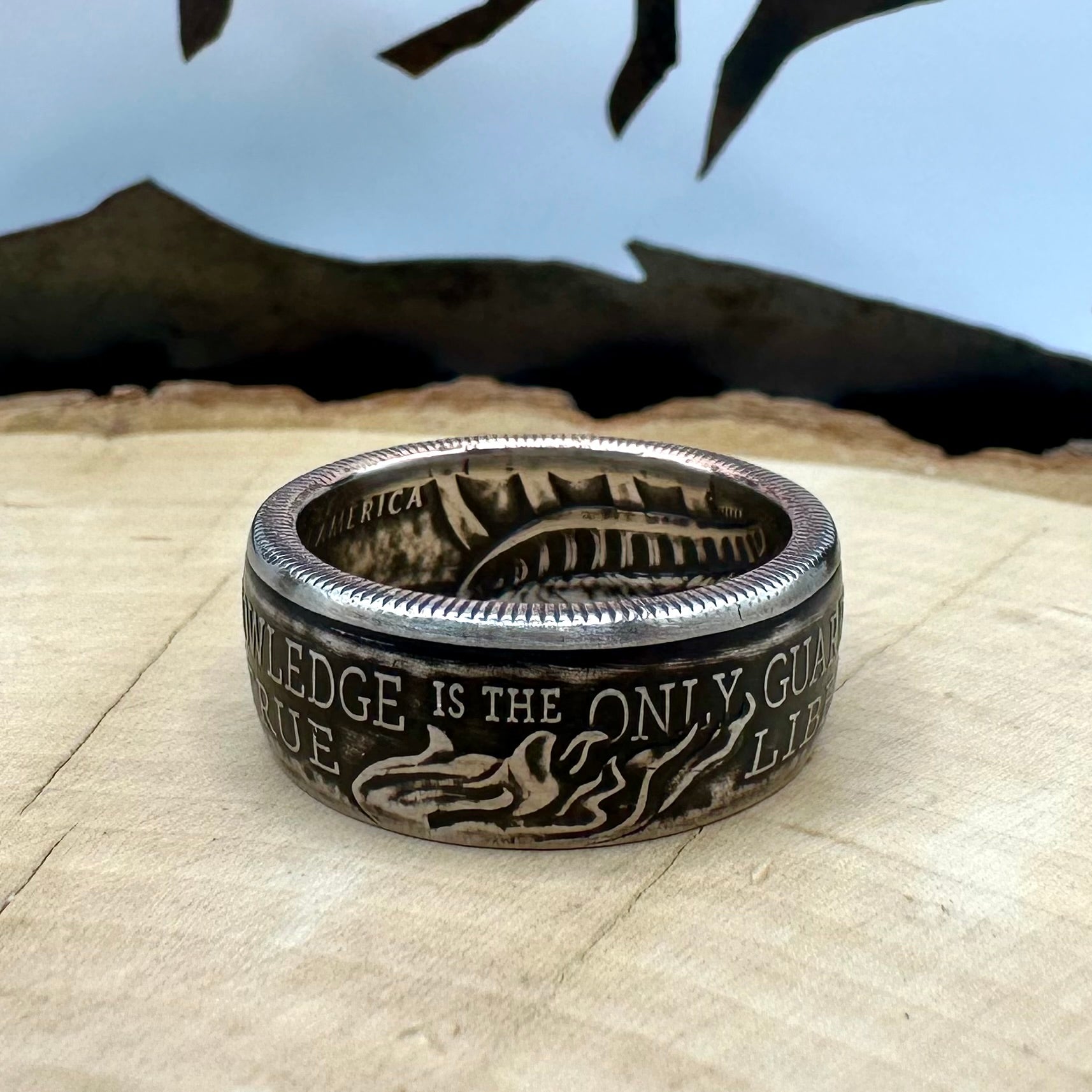 U.S. 2026 Half Dollar Coin Ring on a light wood round with a metal mountain background. - Mountainstruck Coin Jewelry