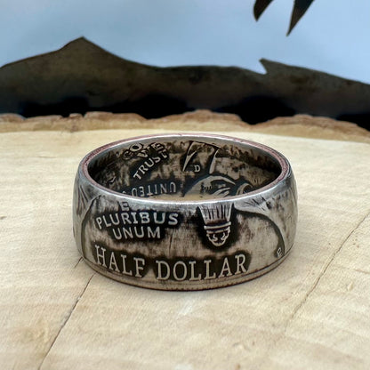 U.S. 2026 Half Dollar Coin Ring on a light wood round with a metal mountain background. - Mountainstruck Coin Jewelry