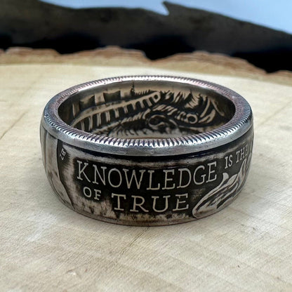 U.S. 2026 Half Dollar Coin Ring on a light wood round with a metal mountain background. - Mountainstruck Coin Jewelry
