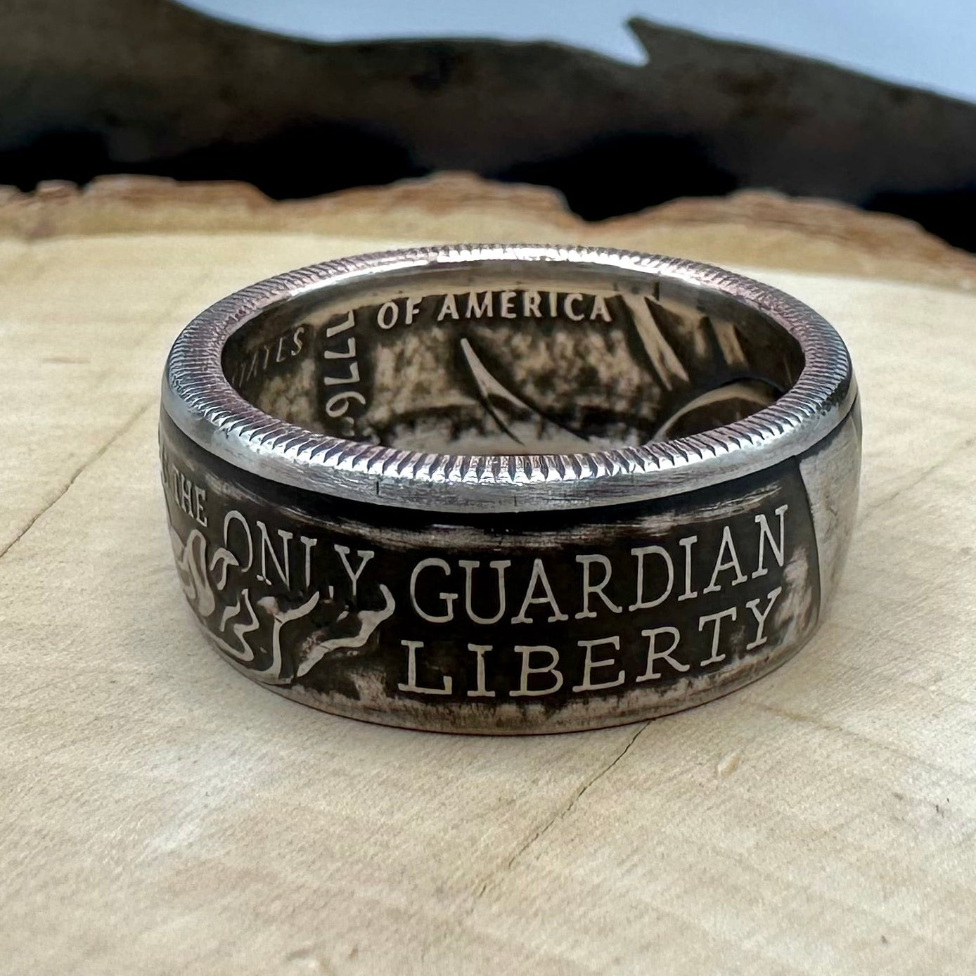U.S. 2026 Half Dollar Coin Ring on a light wood round with a metal mountain background. - Mountainstruck Coin Jewelry