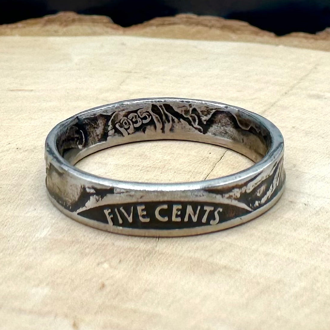 U.S. Buffalo Nickel Coin Ring on a light wood round with a metal mountain background. - Mountainstruck Coin Jewelry