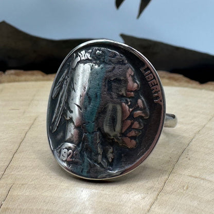 U.S. Buffalo Nickel Coin Signet Ring (Native side) with a sterling silver band on a light wood round with a metal mountain background. - Mountainstruck Coin Jewelry