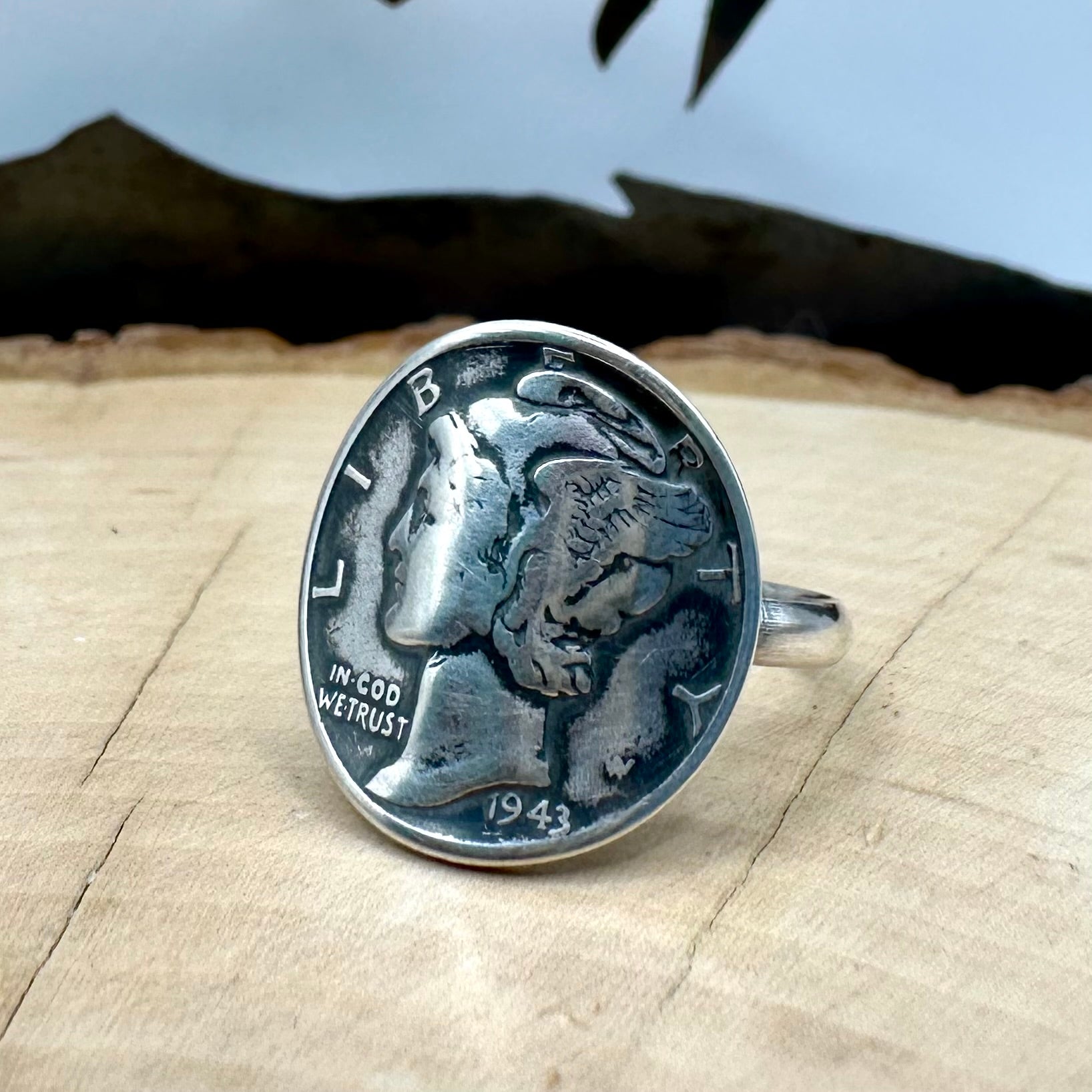 U.S. Mercury Dime Silver Coin Signet Ring with a sterling band on a light wood round with a metal mountain background. - Mountainstruck Coin Jewelry