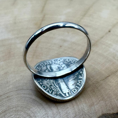 U.S. Mercury Dime Silver Coin Signet Ring with a sterling band on a light wood round with a metal mountain background. - Mountainstruck Coin Jewelry
