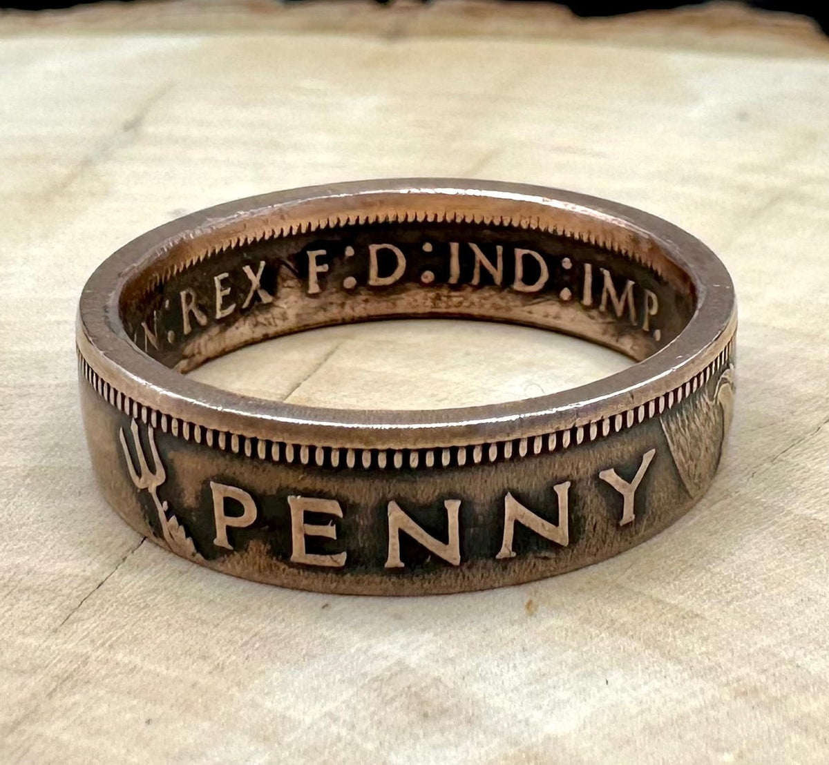 UK One Penny Coin Ring on a light wood round with metal mountain background. - Mountainstruck Coin Jewelry