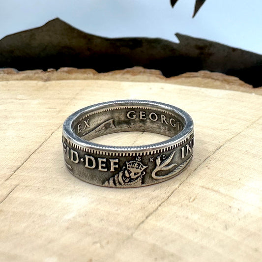 UK One Shilling Silver Coin Ring (patina) on a light wood round with a mountain outline in the background. - Mountainstruck Coin Jewelry