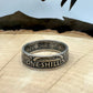 UK One Shilling Silver Coin Ring (patina) on a light wood round with a mountain outline in the background. - Mountainstruck Coin Jewelry
