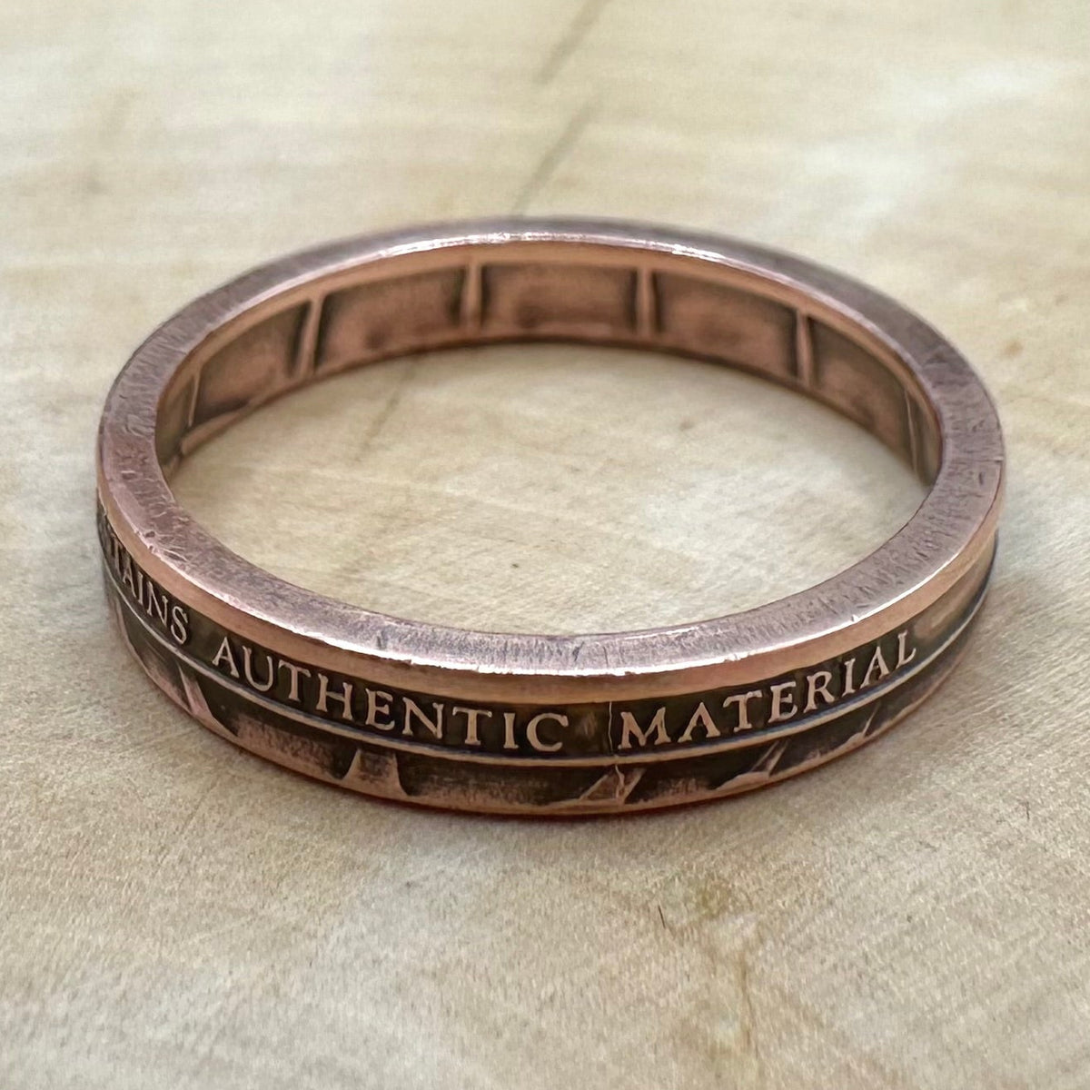 U.S. Authentic Copper Statue of Liberty Token Ring on a light wood background. - Mountainstruck Coin Jewelry