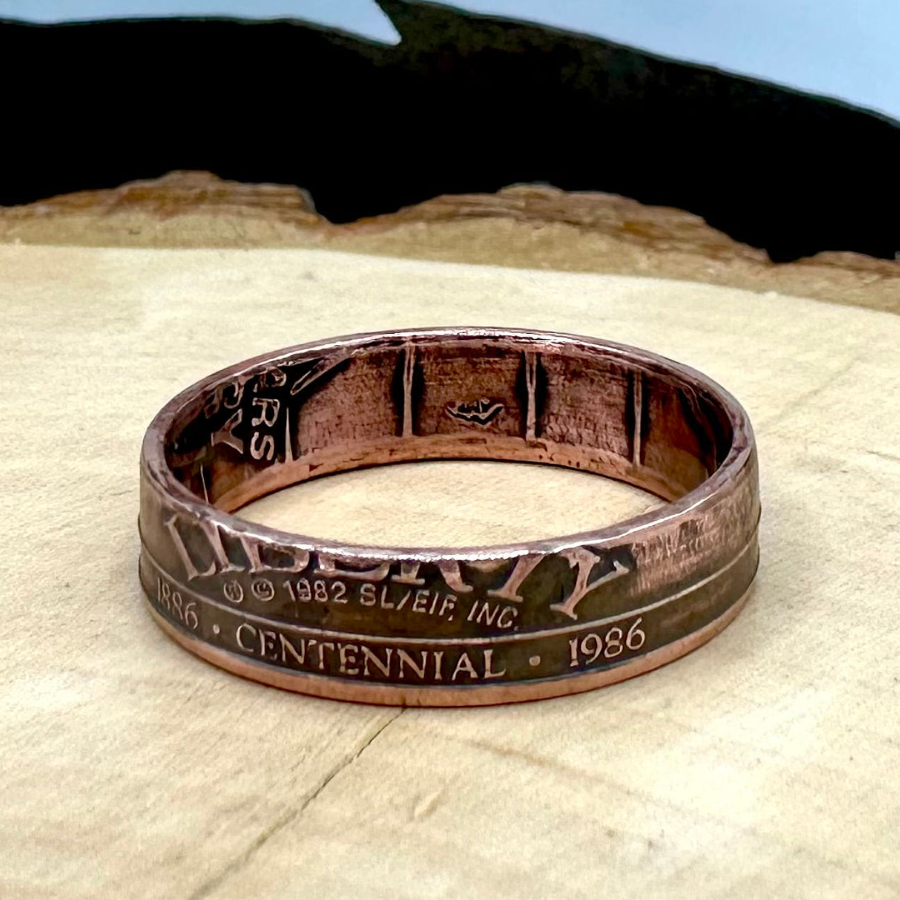 U.S. Authentic Copper Statue of Liberty Token Ring on a light wood background. - Mountainstruck Coin Jewelry