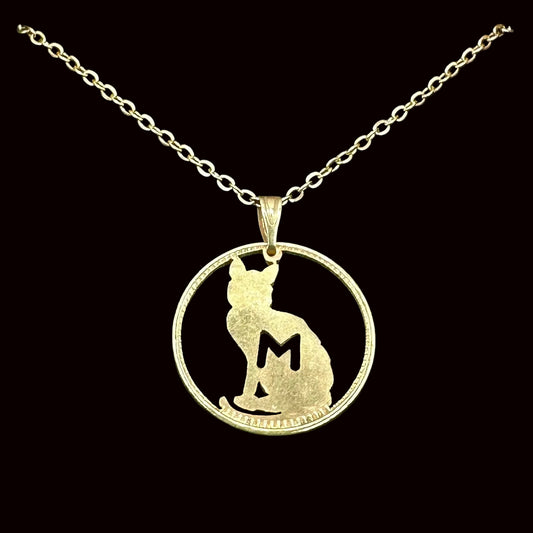 24k Gold Plated Token Necklace with a cat-shaped hand cut out on a black background. 
- Mountainstruck Coin Jewelry