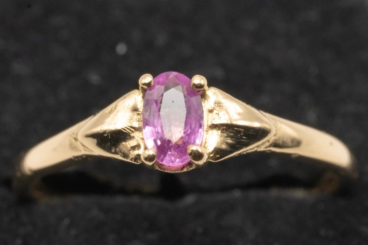 Up close image of a gold band ring with an oval light pink tourmaline stone in center. - Mountainstruck Coin Jewelry
