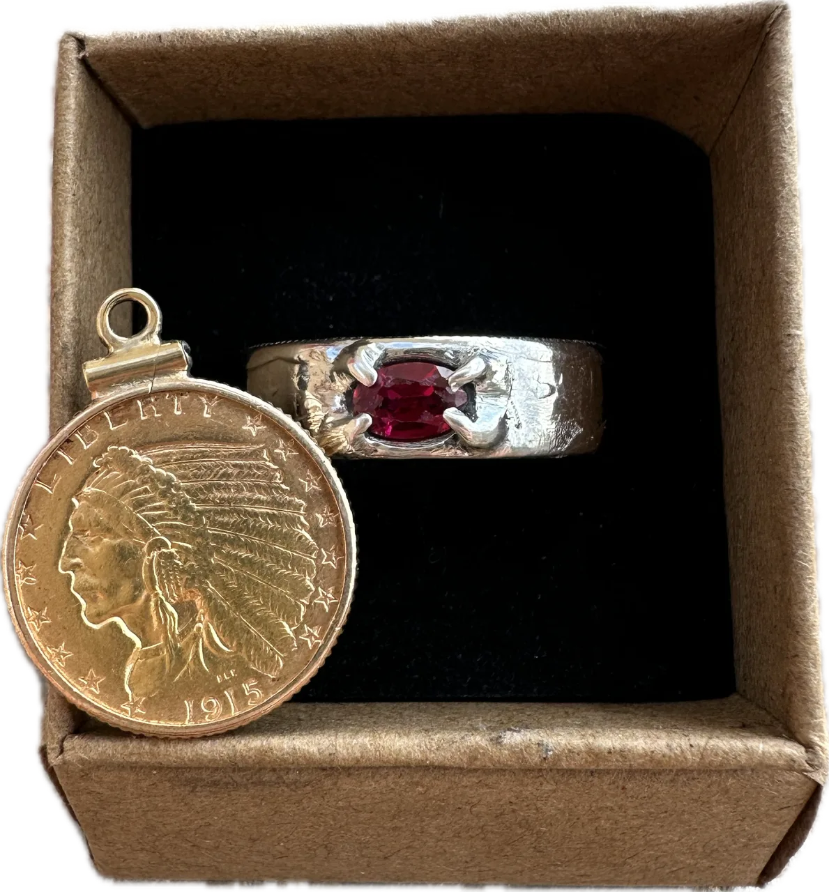 Gold coin with Indian head design and silver ring with red ruby in a brown kraft box on a black velvet background. - Mountainstruck Coin Jewelry