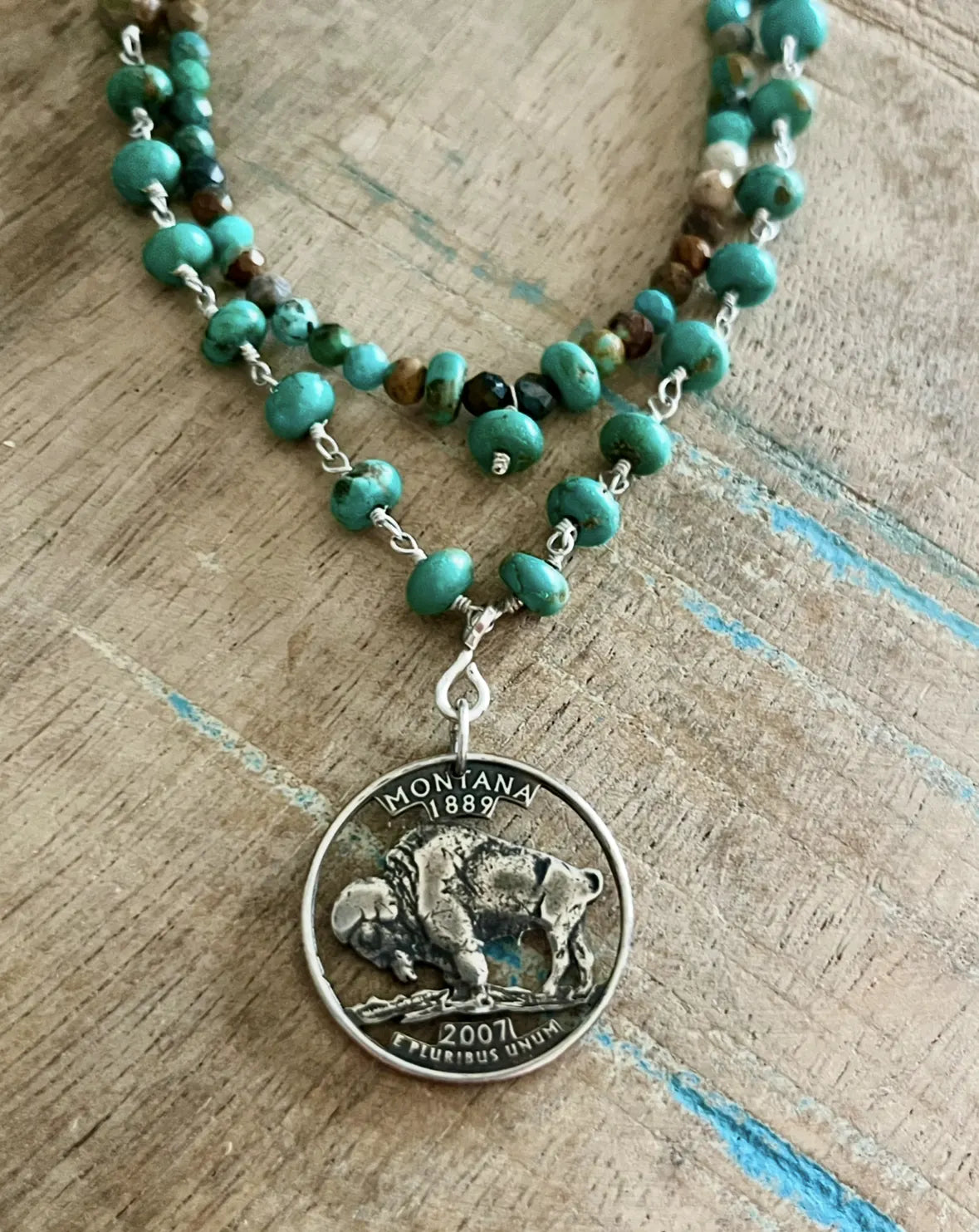 Necklace with turquoise beads and a Montana Quarter/Buffalo Nickel pendant on a wooden surface. - Mountainstruck Coin Jewelry
