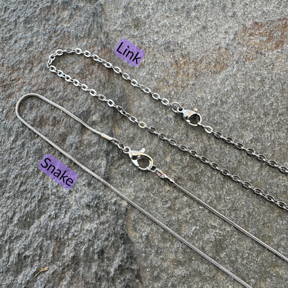 Link chain and snake chains set on a gray stone surface with black text and light purple background for each type of chain. 
- Mountainstruck Coin Jewelry