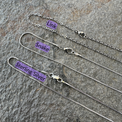 Link chain, snake chain, and sterling silver chains set on a gray stone surface with black text and light purple background for each type of chain. 
- Mountainstruck Coin Jewelry