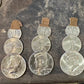 2024 Snowman Coin Christmas Ornament with a selection of U.S. coins (penny, dime, Idaho Quarter, and 2024 uncirculated half dollar) soldered into a snowman with a red ribbon scarf and golden tassel  on a metal background. - Mountainstruck Coin Jewelry