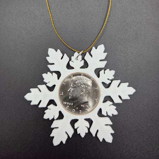 2025 Half Dollar Christmas Ornament  with an uncirculated half dollar cased inside a white 3D printed snowflake with golden tassel on a black background. - Mountainstruck Coin Jewelry