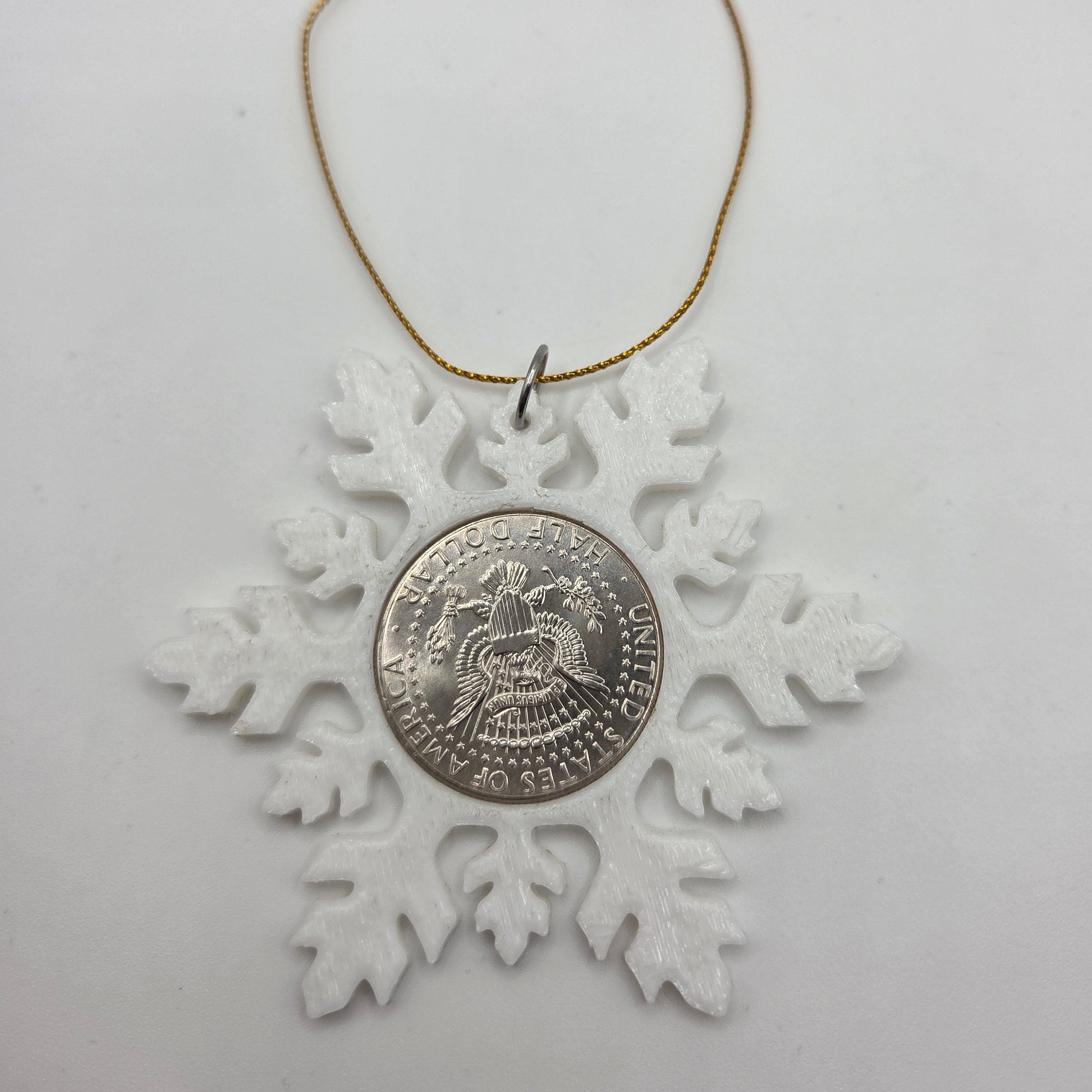 2025 Half Dollar Christmas Ornament  with an uncirculated half dollar cased inside a white 3D printed snowflake with golden tassel on a white background. - Mountainstruck Coin Jewelry