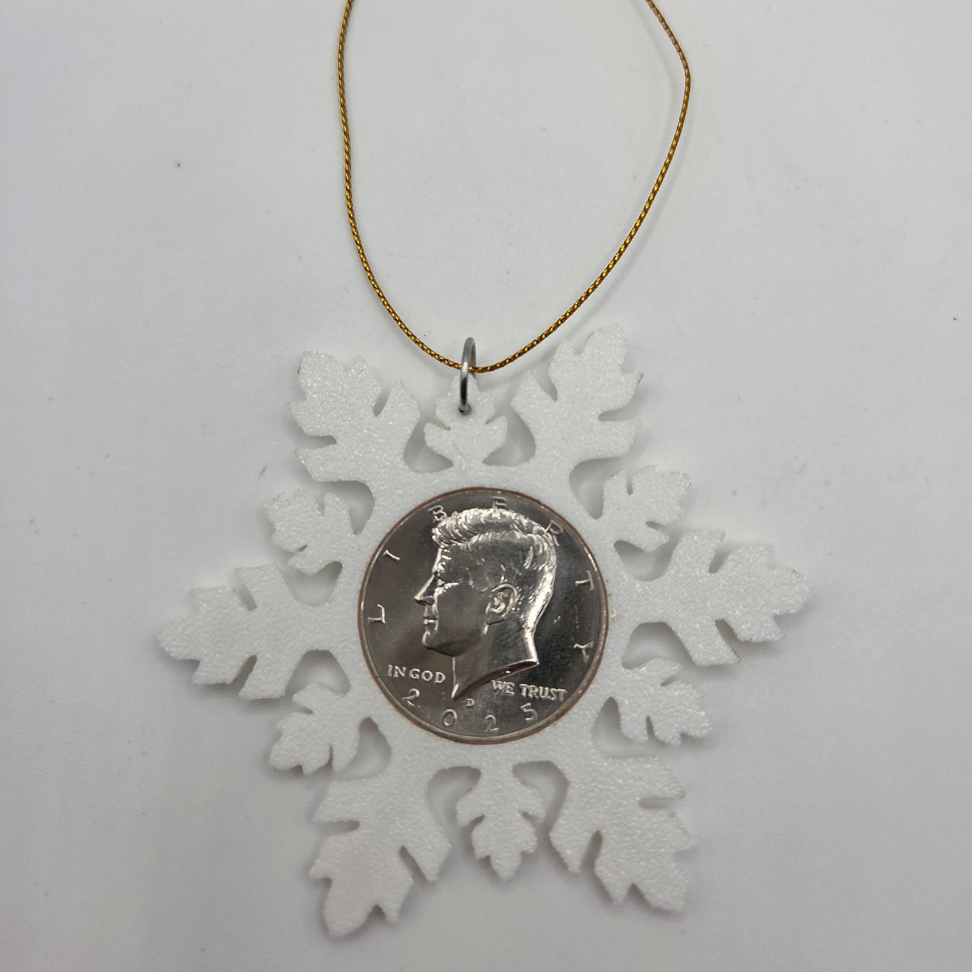 2025 Half Dollar Christmas Ornament  with an uncirculated half dollar cased inside a white 3D printed snowflake with golden tassel on a white background. - Mountainstruck Coin Jewelry