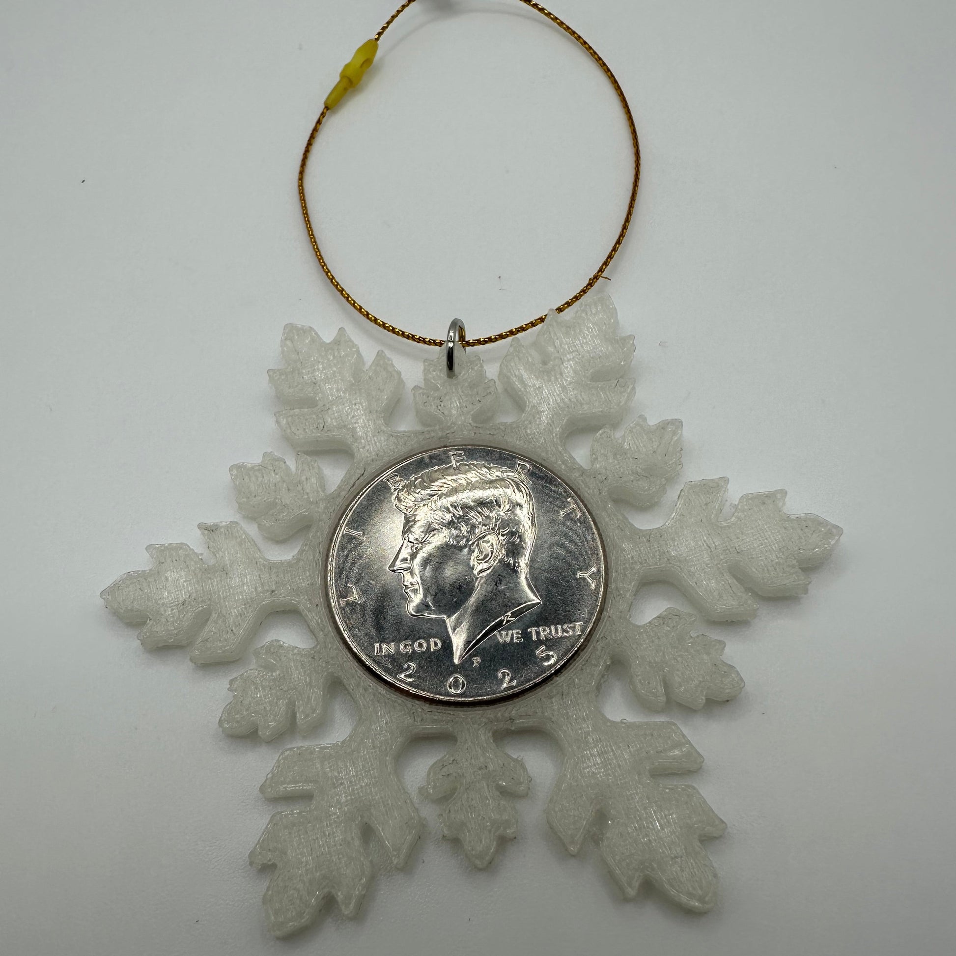 2025 Half Dollar Christmas Ornament (glows) with an uncirculated half dollar cased inside a white 3D printed snowflake with golden tassel on a white background. - Mountainstruck Coin Jewelry