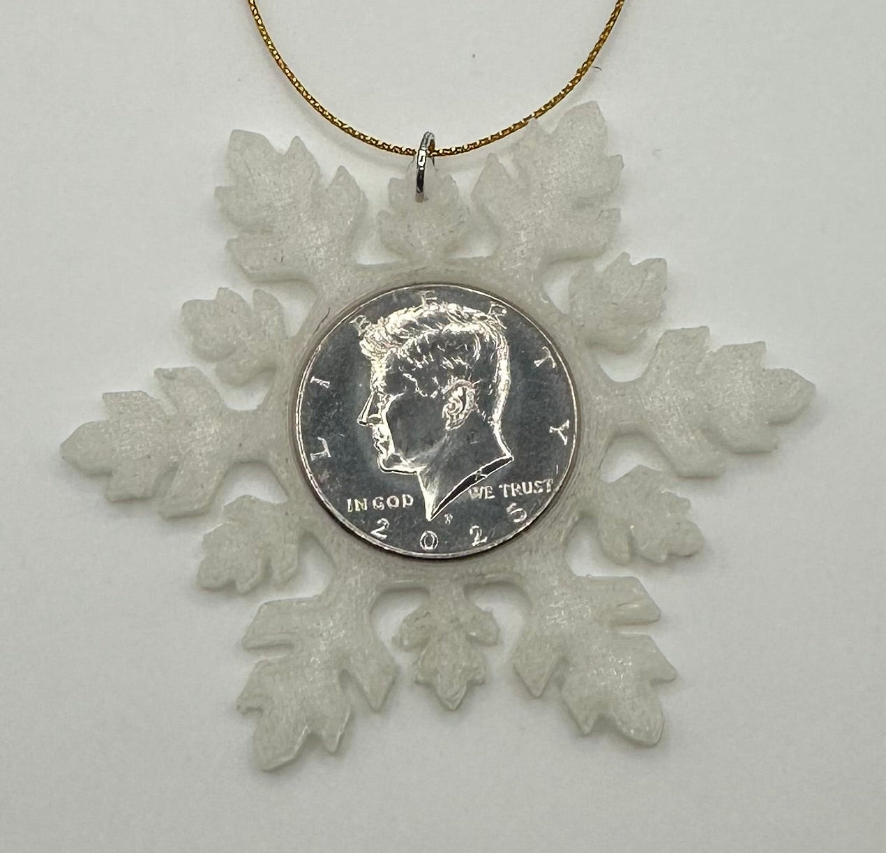 2025 Half Dollar Christmas Ornament (glows) with an uncirculated half dollar cased inside a white 3D printed snowflake with golden tassel on a white background. - Mountainstruck Coin Jewelry