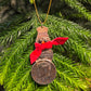2025 Snowman Coin Christmas Ornament with a selection of U.S. coins (penny, dime, state quarter, and 2025 uncirculated half dollar) soldered into a snowman with a red ribbon scarf and golden tassel in front of a green pine tree. - Mountainstruck Coin Jewelry