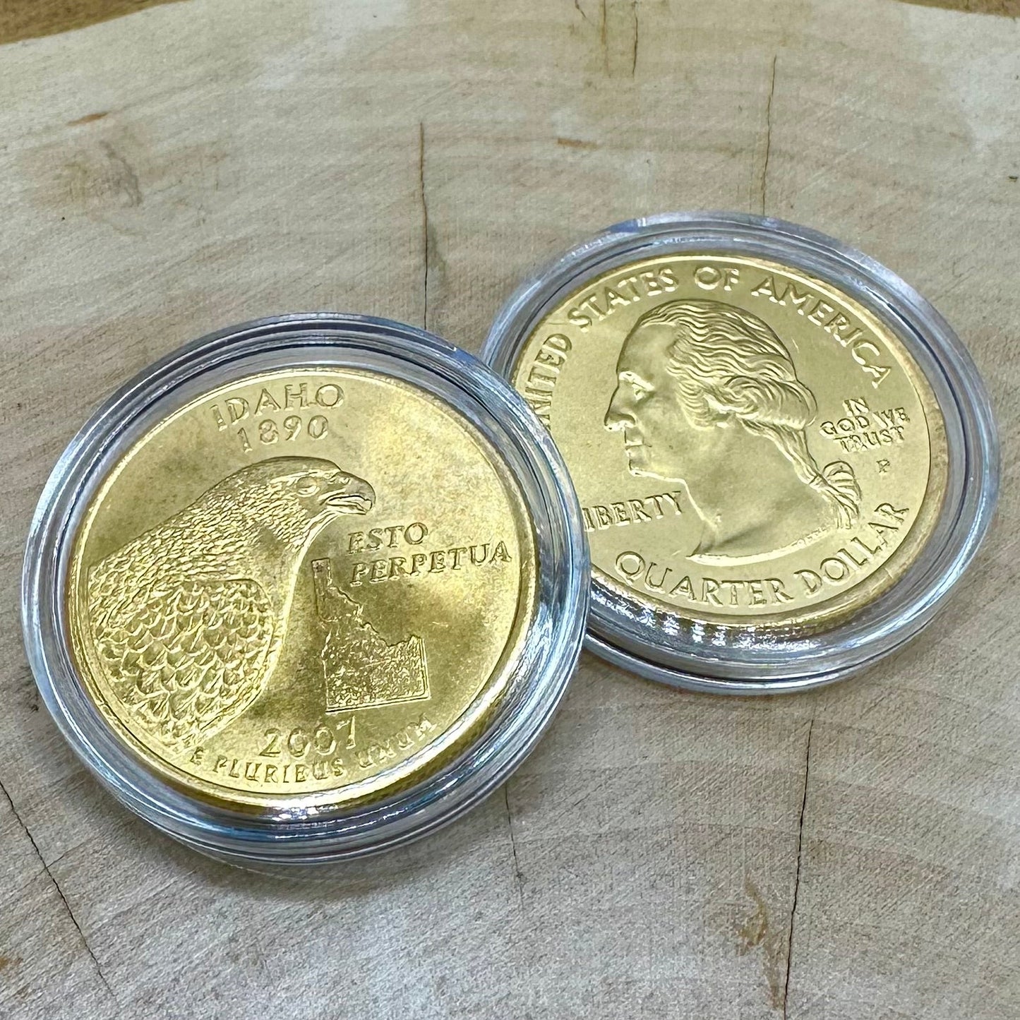 U.S. Idaho State Quarter 24k Gold Plated Coin plated with Idaho Gold in a plastic case front on left side and back on right side of photo on a light wood round.
- Mountainstruck Coin Jewelry