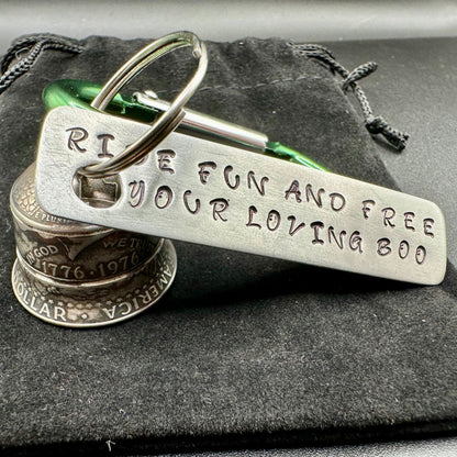Green keychain with engraved text "ride fun and free your loving boo" on a metal surface with a gremlin bell made of coins. 
- Mountainstruck Coin Jewelry