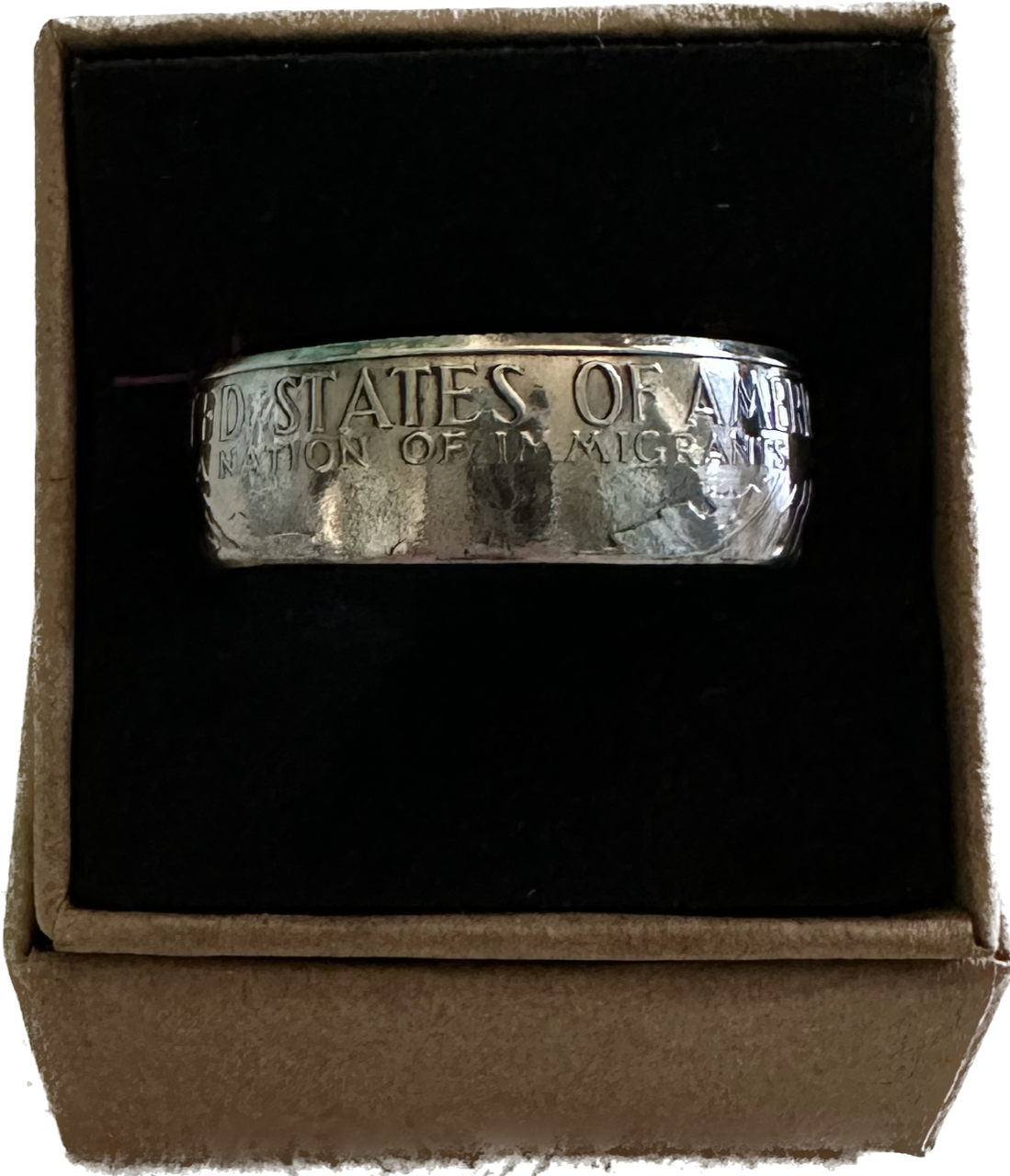 "A Nation of Immigrants" Half Dollar Coin Ring shined in a brown kraft box on a black velvet background. - Mountainstruck Coin Jewelry