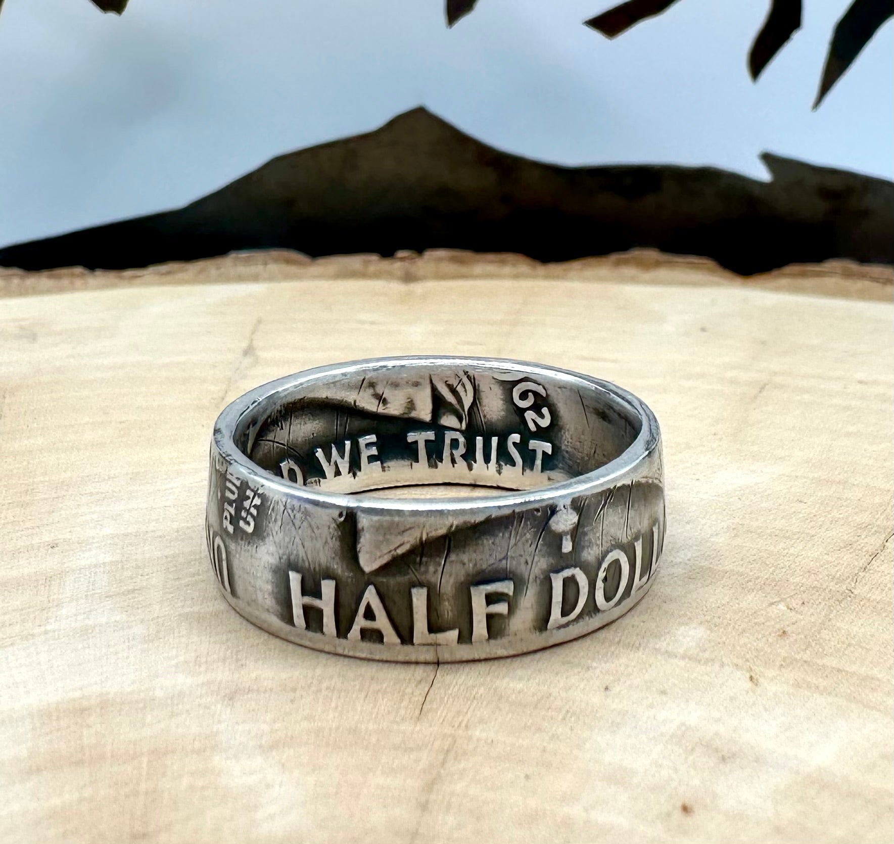 Ben Franklin Half Dollar Silver Coin Ring on a light wood round with a metal mountain background. - Mountainstruck Coin Jewelry