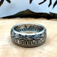 Morgan Dollar Silver Coin Ring patina on a light wood round with a metal mountain background. - Mountainstruck Coin Jewelry