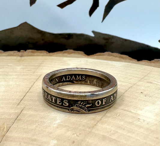 Presidential Dollar Coin Ring (Reverse) patina on a light wood round with a metal mountain background. - Mountainstruck Coin Jewelry