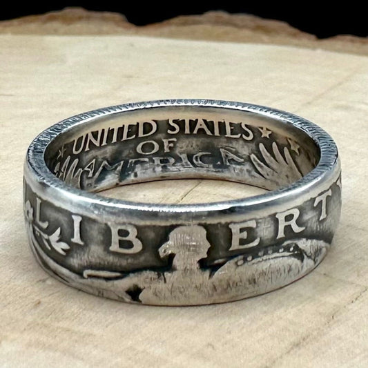 U.S. Standing Liberty Quarter Silver Coin Ring a light wood round with a metal mountain background. - Mountainstruck Coin Jewelry