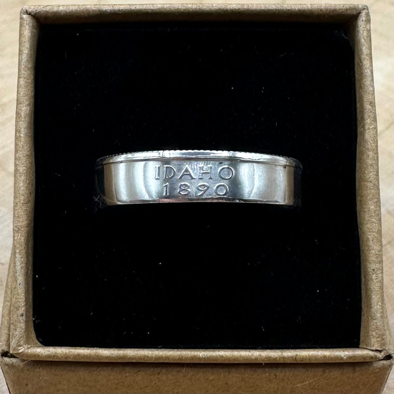U.S. State Quarter Silver Coin Ring featuring Idaho in a brown kraft box on a black velvet background. - Mountainstruck Coin Jewelry