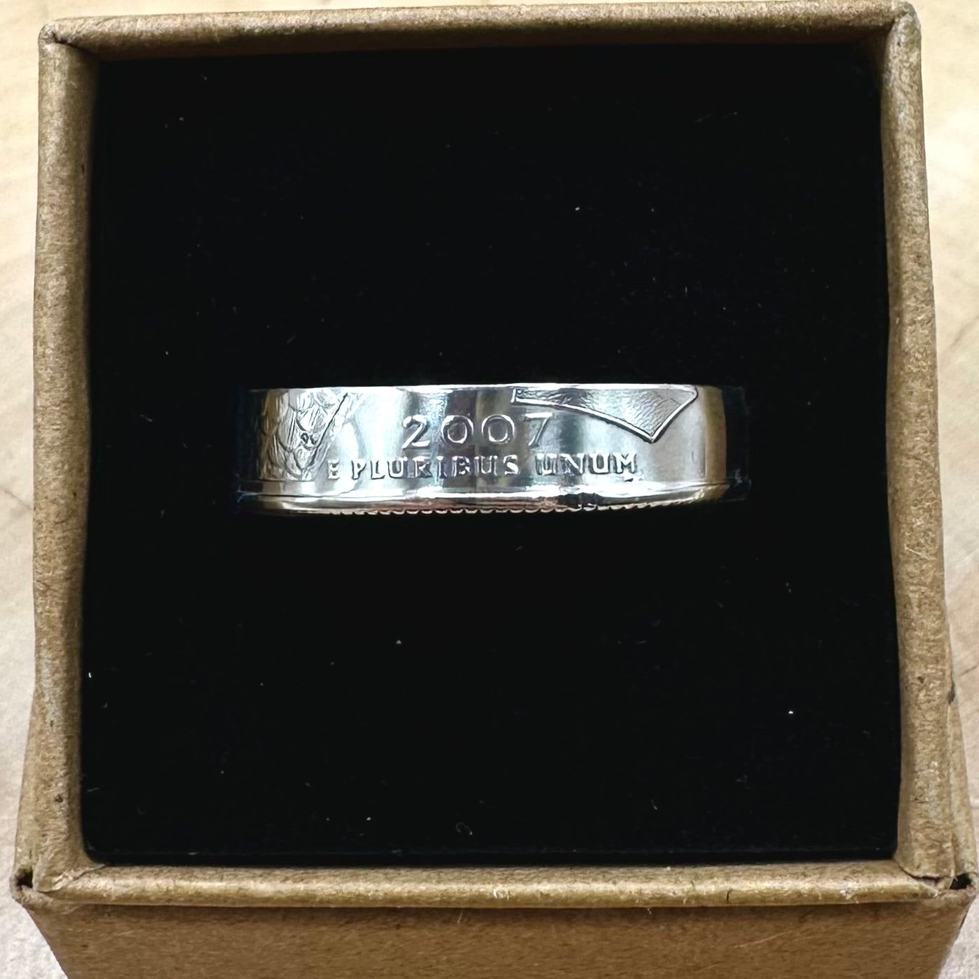 U.S. State Quarter Silver Coin Ring featuring Idaho and year the coin was minted in a brown kraft box on a black velvet background. - Mountainstruck Coin Jewelry