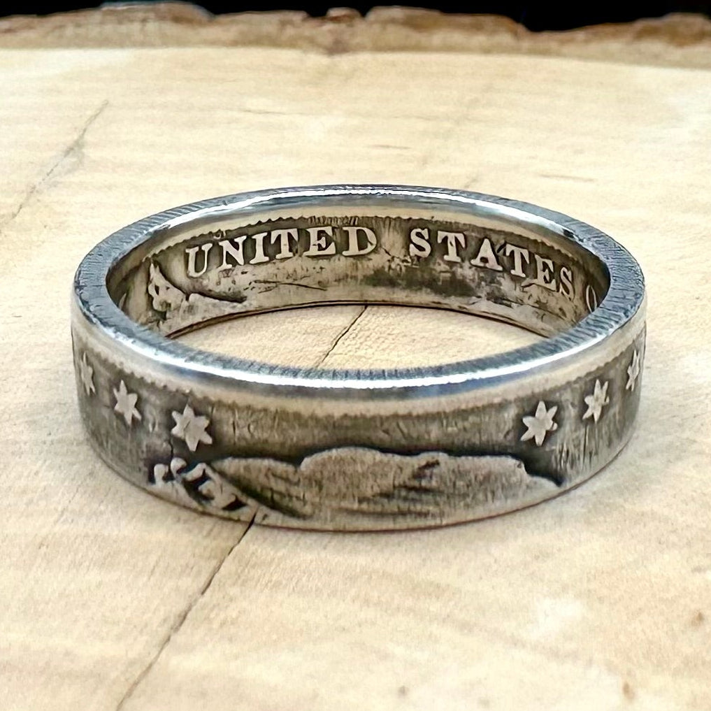 U.S. Capped Bust Liberty Quarter Silver Coin Ring on a light wood round with metal mountain background. - Mountainstruck Coin Jewelry