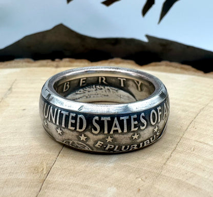 U.S. Eisenhower One Dollar 40% Silver Coin Ring on a light wood round with a metal mountain background. - Mountainstruck Coin Jewelry