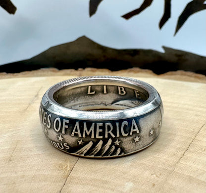 U.S. Eisenhower One Dollar 40% Silver Coin Ring on a light wood round with a metal mountain background. - Mountainstruck Coin Jewelry