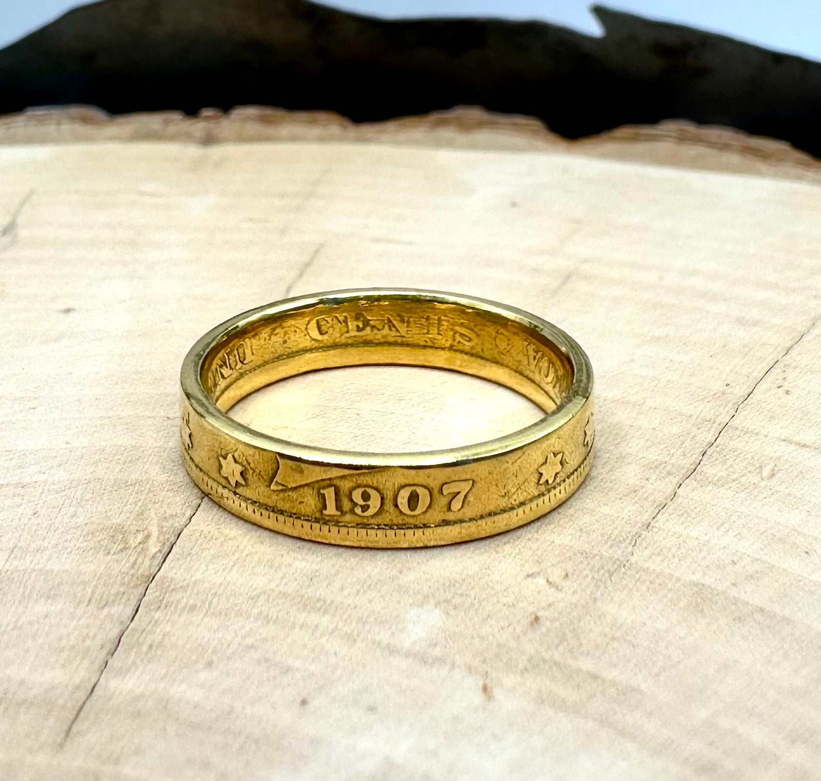 U.S. "V" Nickel Coin Ring 24k gold plated on a light wood round with a metal mountain background. - Mountainstruck Coin Jewelry