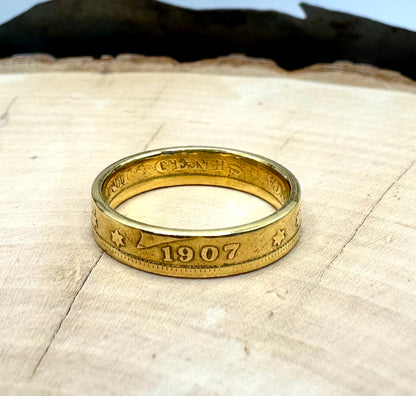 U.S. "V" Nickel Coin Ring 24k gold plated on a light wood round with a metal mountain background. - Mountainstruck Coin Jewelry