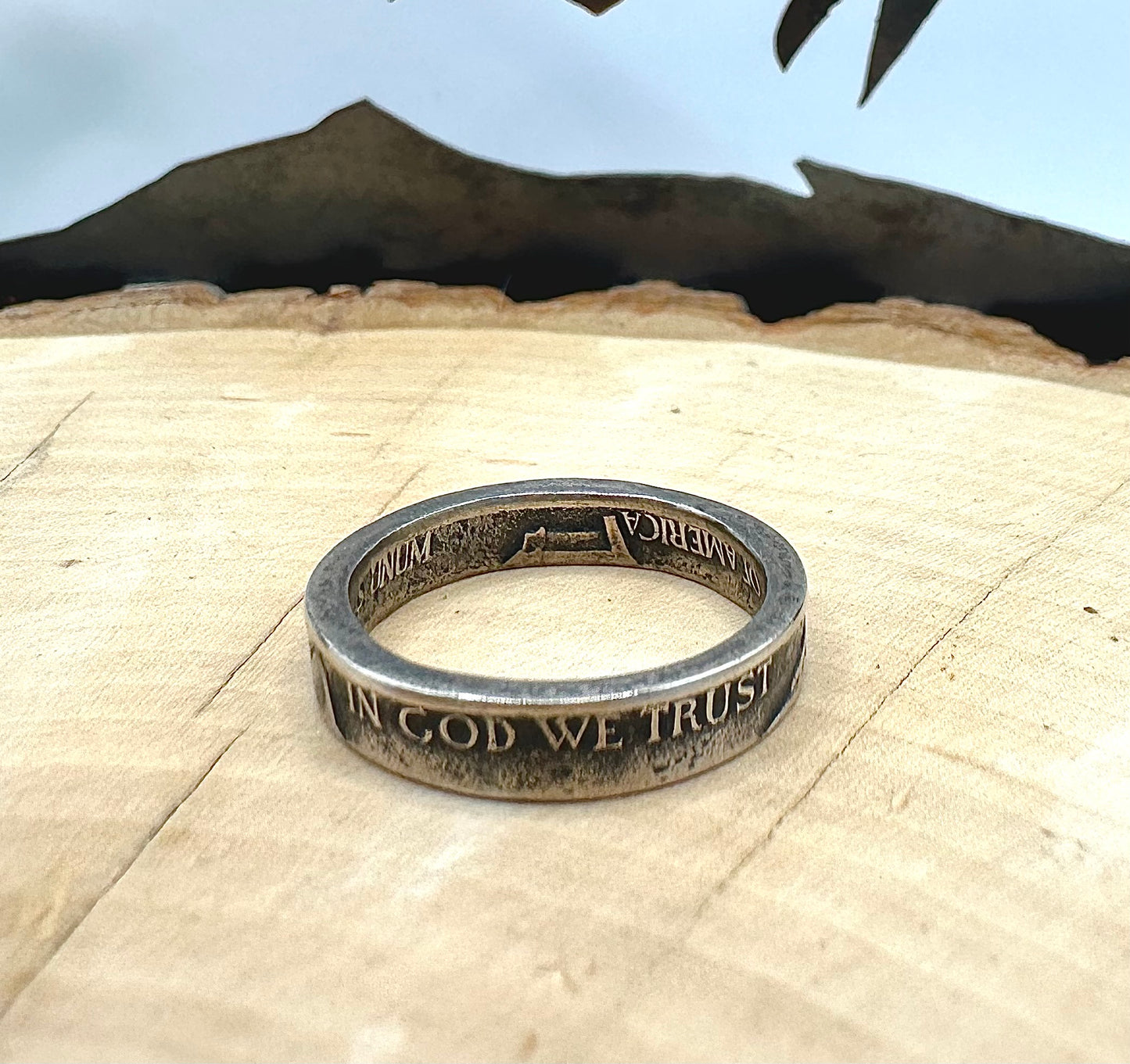 WW2 Nickel Silver Coin Ring on a light wood round with a metal mountain background. - Mountainstruck Coin Jewelry