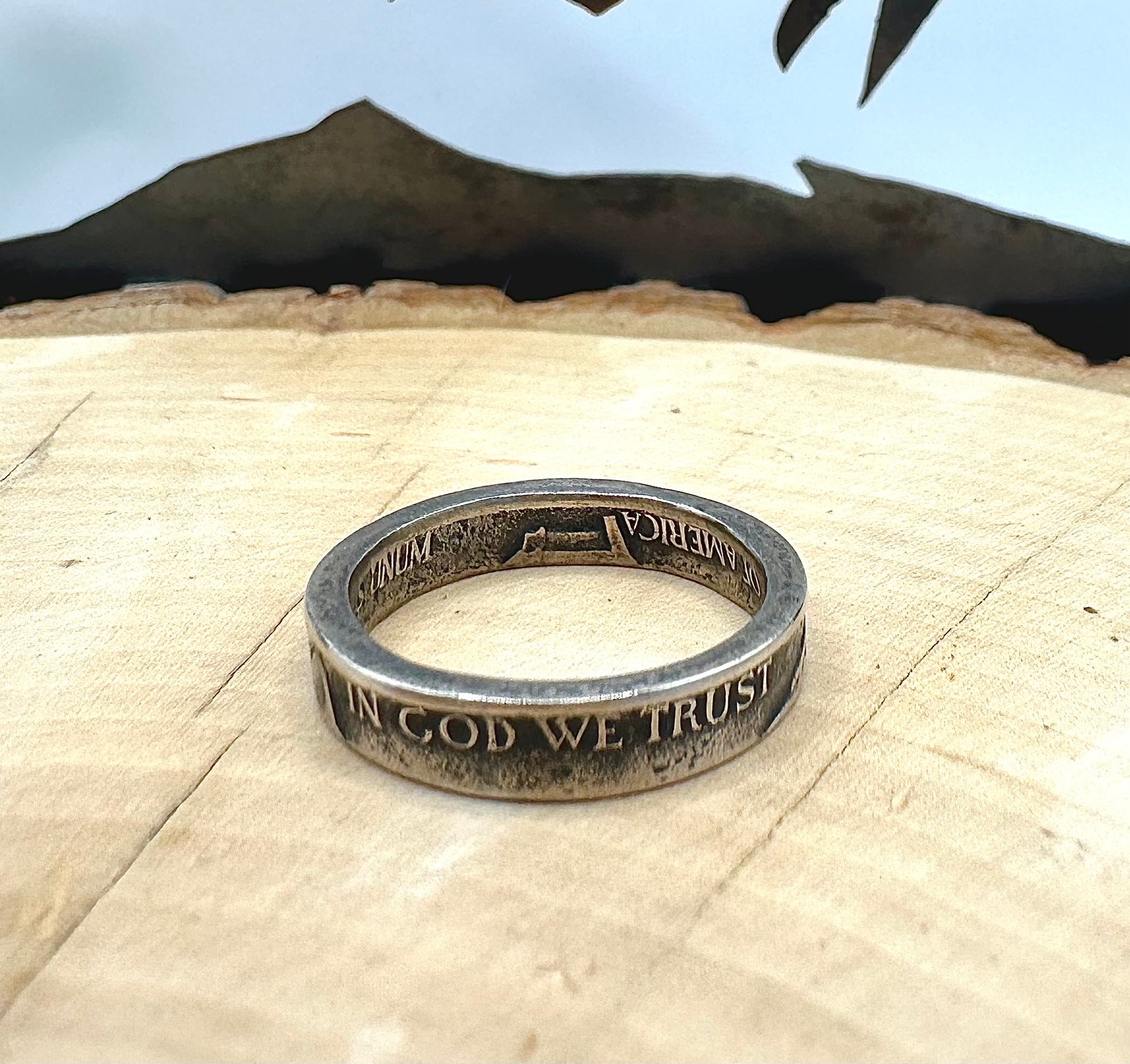 WW2 Nickel Silver Coin Ring on a light wood round with a metal mountain background. - Mountainstruck Coin Jewelry