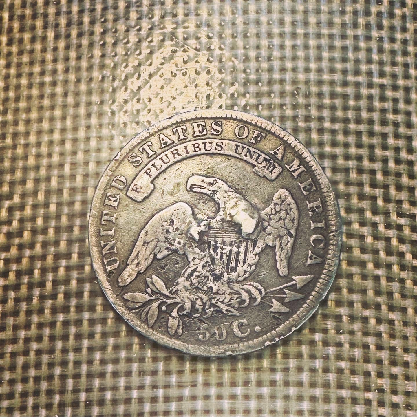 U.S. (Rare) Capped Bust Liberty Silver Half Dollar back of coin on a plastic woven background. - Mountainstruck Coin Jewelry