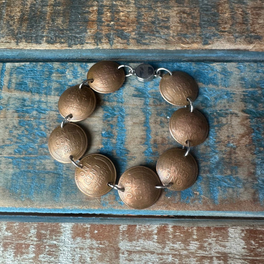 Wheat Penny Domed Coin Bracelet on a multicolored wood background.